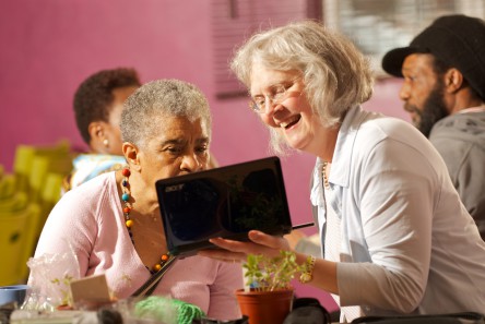 Women at Age UK meeting checking out tablet PC
